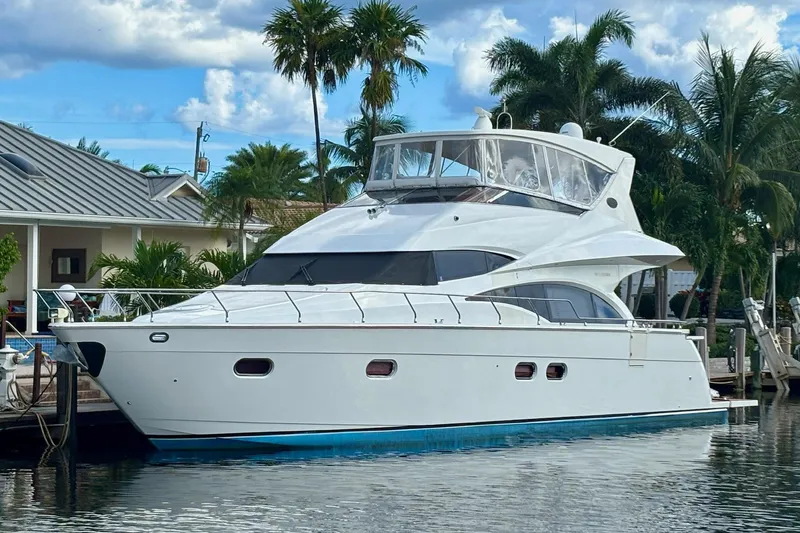The Image of Luxury 2004 Marquis 59 yacht docked by palm trees and waterfront homes. - 0