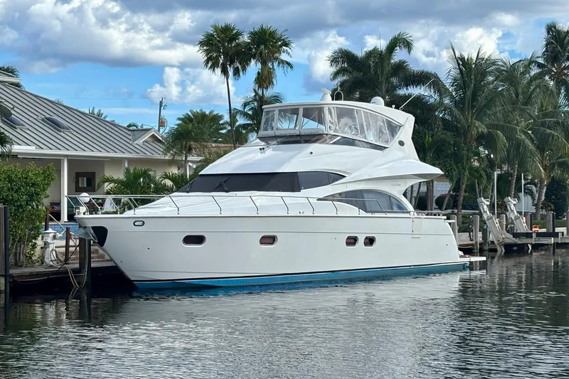 Slide: The Image of Luxury 2004 Marquis 59 yacht docked by palm trees and waterfront homes. - 1