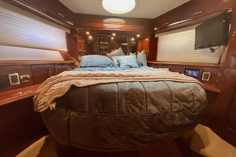 Slide: The Image of Luxurious 2004 Marquis 59 yacht bedroom with cozy bedding and elegant wood finishes. - 30