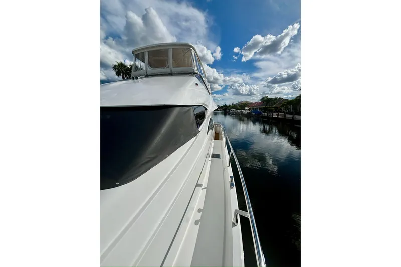 Slide: The Image of 2004 Marquis 59 yacht on a serene waterway under a partly cloudy sky. - 8