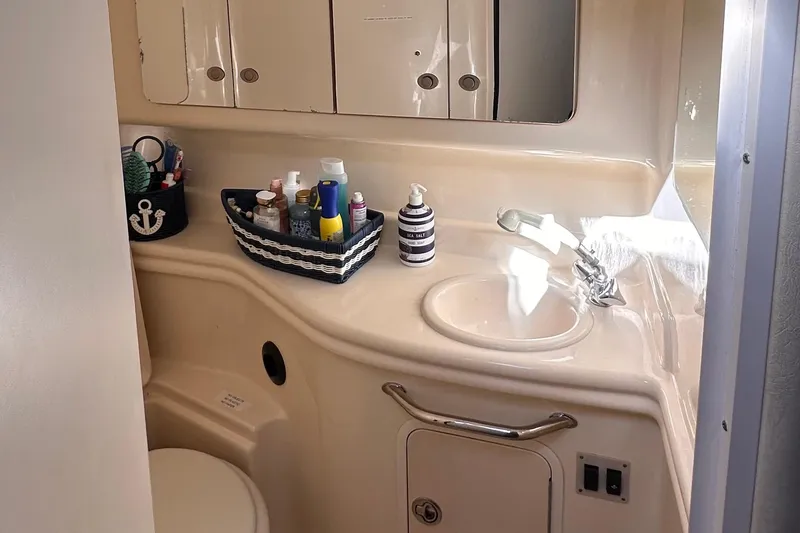 Slide: The Image of 2005 Sea Ray 320 Sundancer bathroom with sink, toiletries, and storage cabinets. - 12