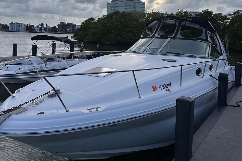 The Image of 2005 Sea Ray 320 Sundancer docked by the waterfront, with overcast skies. - 2