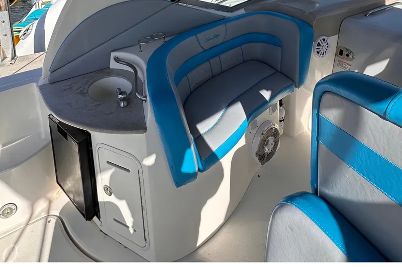 Slide: The Image of 2005 Sea Ray 320 Sundancer interior with blue and white seating, sink, and mini fridge. - 4
