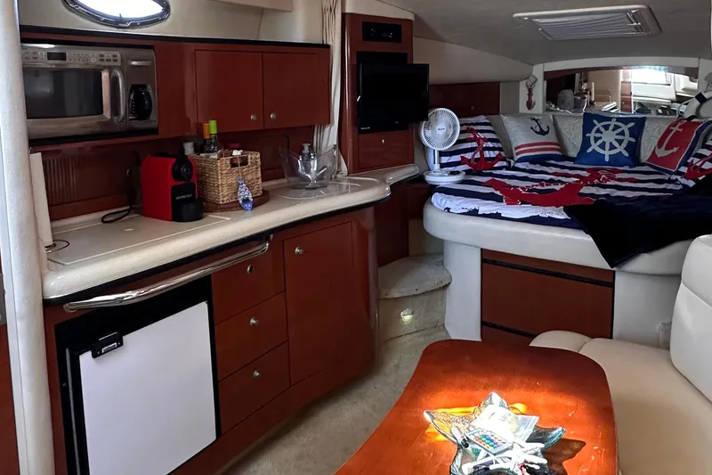 Slide: The Image of 2005 Sea Ray 320 Sundancer cabin with kitchenette and nautical-themed bedding. - 9