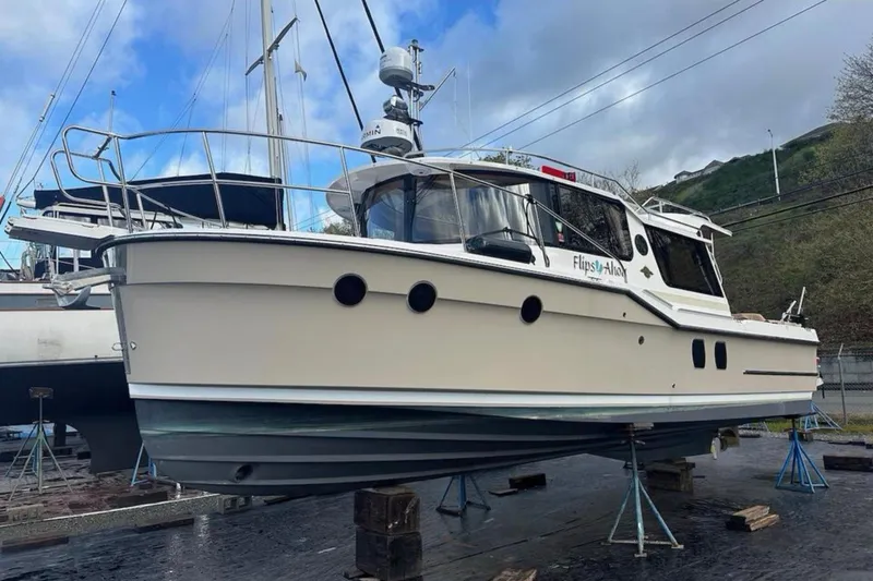 Slide: The Image of 2021 Ranger Tugs R-29 S with covered deck, docked near reeds and trees. - 3