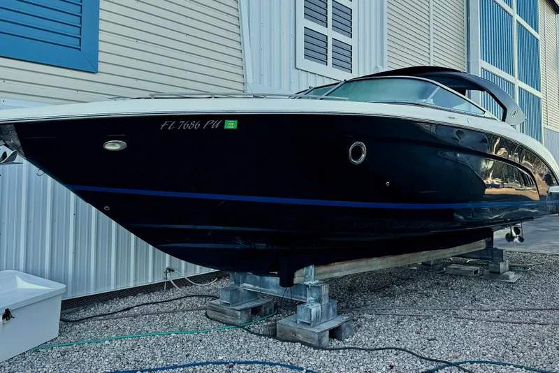 Slide: The Image of 2014 Regal 3200 Bowrider boat on dry dock, blue hull, near a building. - 10