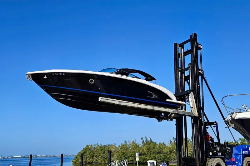 Slide: The Image of 2014 Regal 3200 Bowrider boat lifted by forklift against clear blue sky. - 2