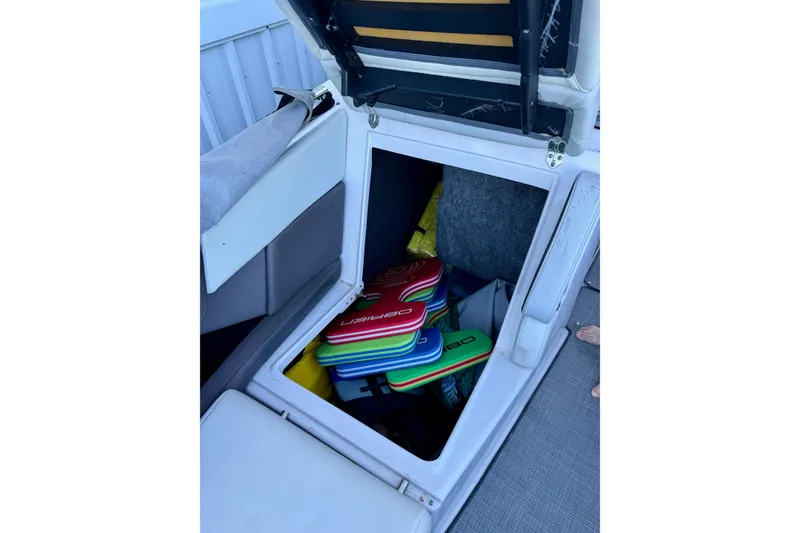 Slide: The Image of Open storage compartment in 2014 Regal 3200 Bowrider boat with colorful kneeboards. - 24