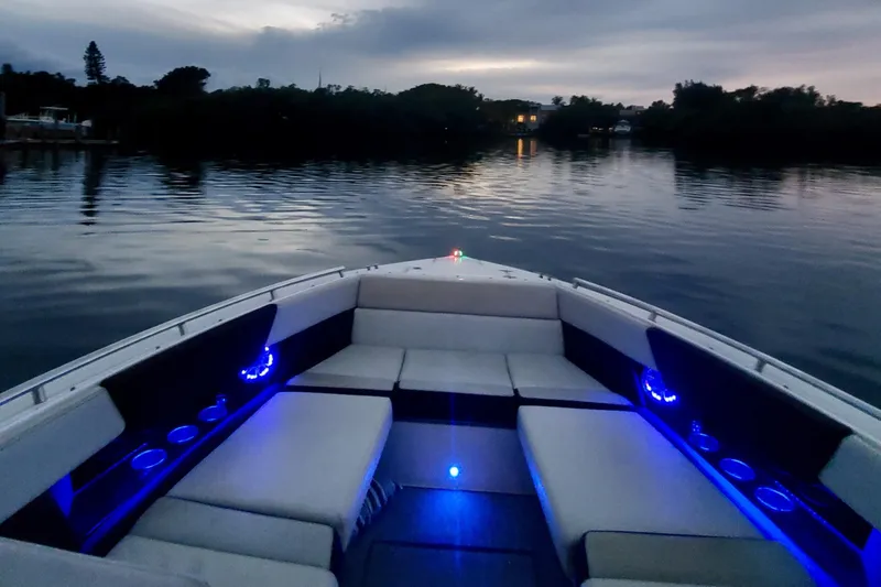 Slide: The Image of 2014 Regal 3200 Bowrider boat with illuminated seating at dusk on calm water. - 3