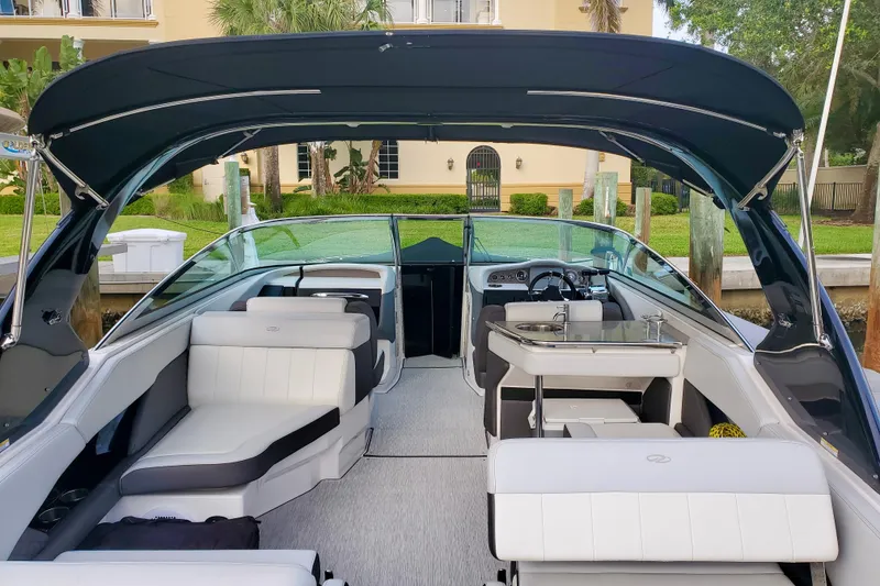 Slide: The Image of 2014 Regal 3200 Bowrider interior with seating, canopy, and helm, docked near a house. - 5