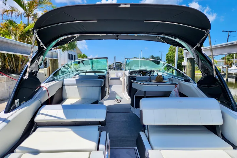 Slide: The Image of 2014 Regal 3200 Bowrider boat interior with seating and canopy, docked under blue sky. - 6