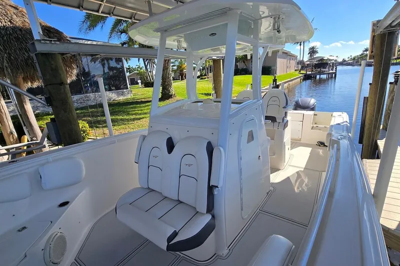 Slide: The Image of 2015 Tidewater 280 CC Adventure boat interior with seating and console, docked by a scenic canal. - 14