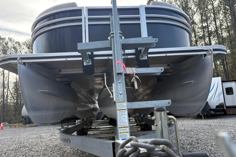 Slide: The Image of 2020 Harris Cruiser 250 pontoon boat on trailer, parked in wooded area. - 25