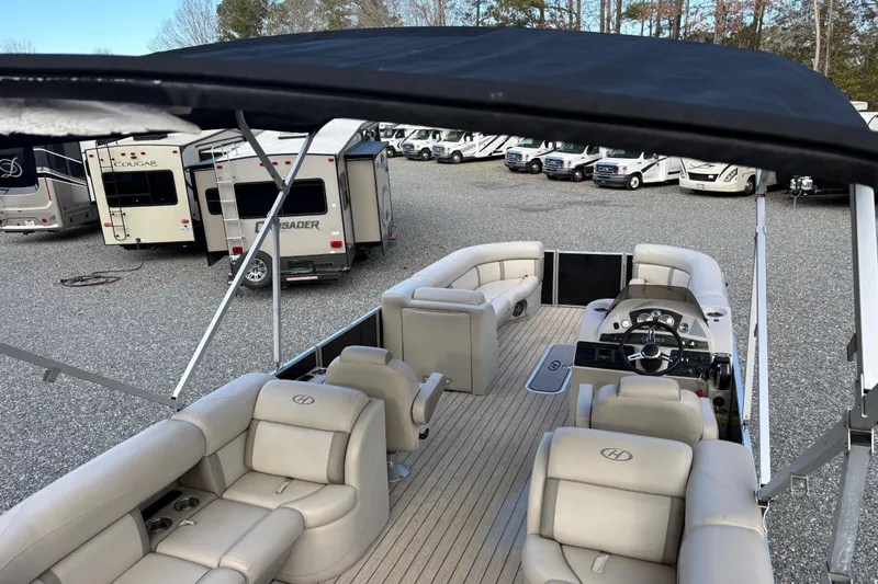 Slide: The Image of 2020 Harris Cruiser 250 pontoon boat with beige seating, parked near RVs. - 36