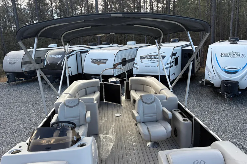 Slide: The Image of 2020 Harris Cruiser 250 pontoon boat with canopy, parked near RVs in a wooded area. - 38