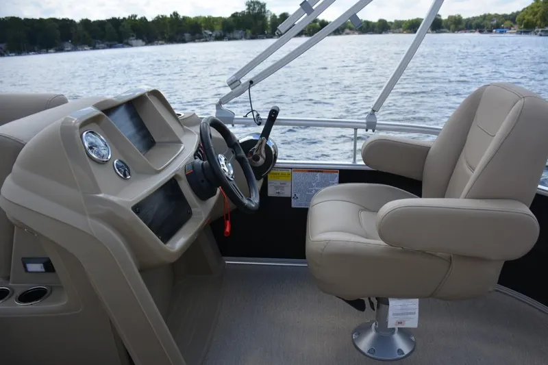 Slide: The Image of 2023 Starcraft LX 16 boat interior with steering wheel and captain's chair on a lake. - 10