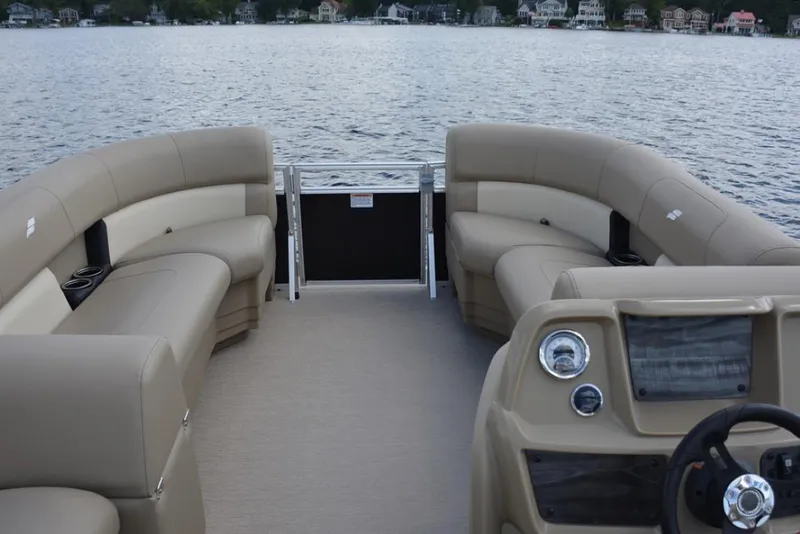 Slide: The Image of 2023 Starcraft LX 16 pontoon boat interior with beige seating on a lake. - 9