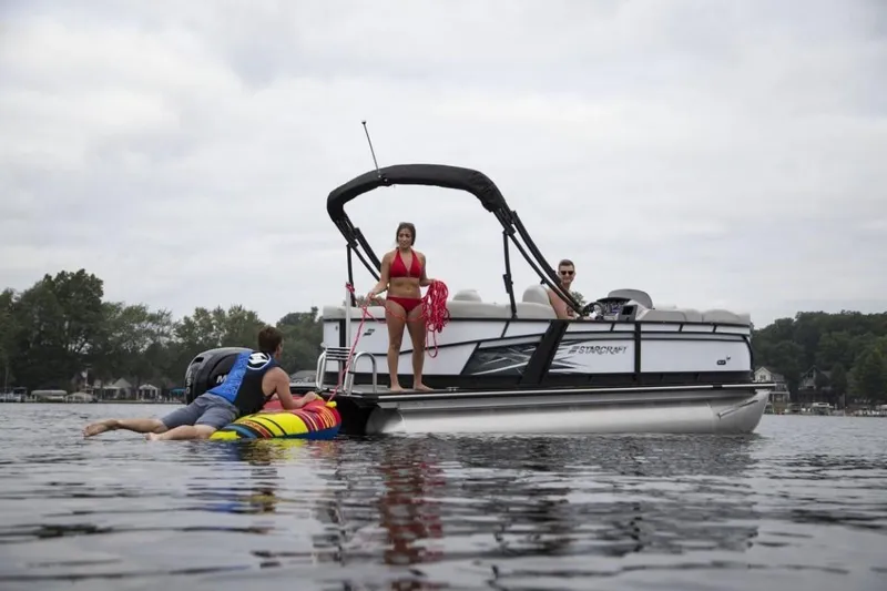 Slide: The Image of 2024 Starcraft SLS 1 pontoon boat with people enjoying water activities. - 2