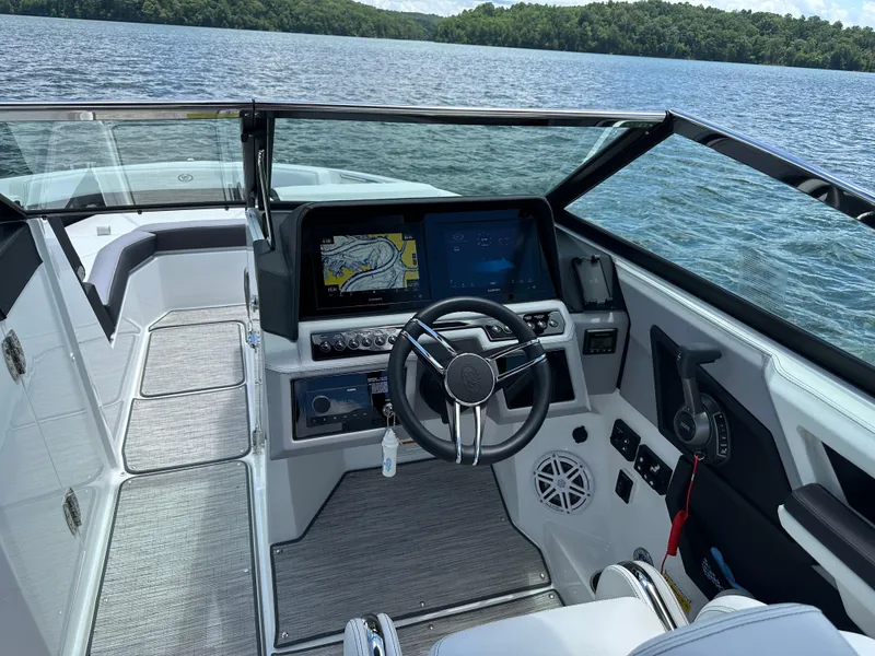 Slide: The Image of 2023 Cobalt R6 boat interior with modern dashboard and steering, on a scenic lake. - 20
