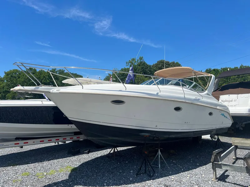 The Image of 1996 Silverton 310 Express boat on stands, outdoors under clear blue sky. - 0