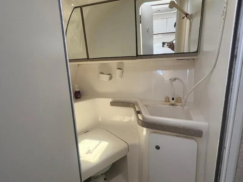 Slide: The Image of 1996 Silverton 310 Express boat bathroom with sink, mirror, and storage cabinets. - 11