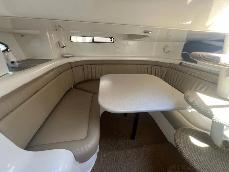 Slide: The Image of 1996 Silverton 310 Express cabin interior with beige seating and table. - 13