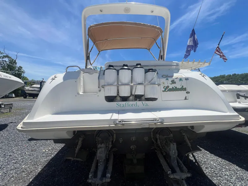 Slide: The Image of 1996 Silverton 310 Express boat, rear view, docked with flags in the background. - 2