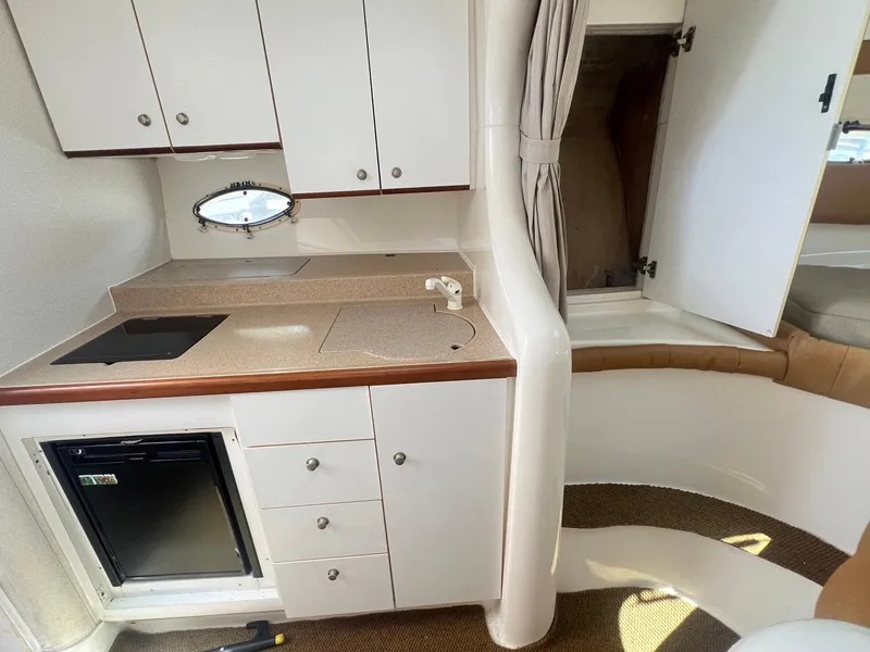 Slide: The Image of 1996 Silverton 310 Express boat interior with kitchenette, cabinets, and compact fridge. - 8