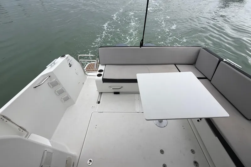 Slide: The Image of 2019 Jeanneau NC 895 boat deck with seating and table on calm water. - 10