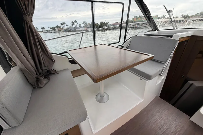 Slide: The Image of 2019 Jeanneau NC 895 interior with seating and table, overlooking marina view. - 15