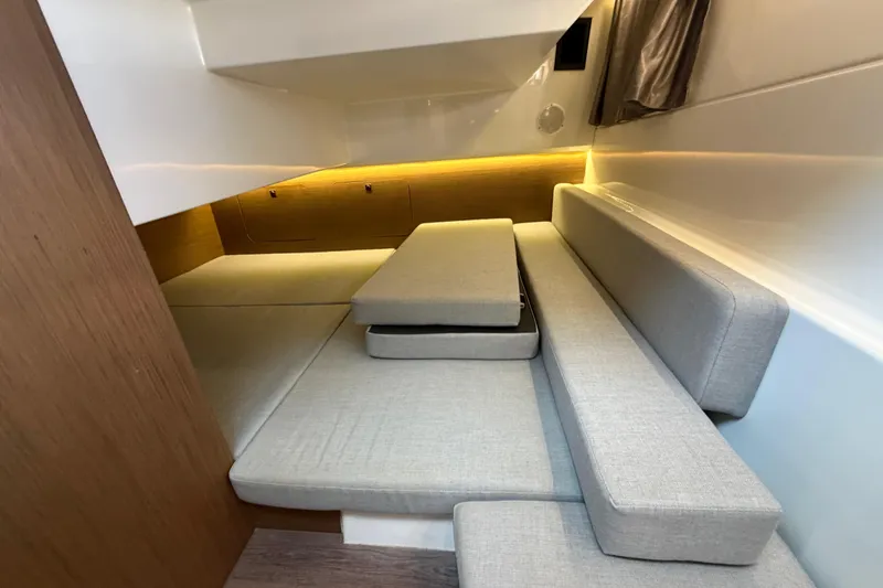 Slide: The Image of 2019 Jeanneau NC 895 interior cabin with gray cushions and wooden accents. - 20