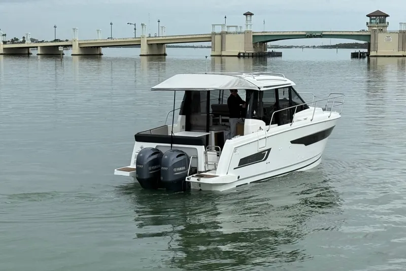 Slide: The Image of 2019 Jeanneau NC 895 boat with twin Yamaha engines on calm water near a bridge. - 4