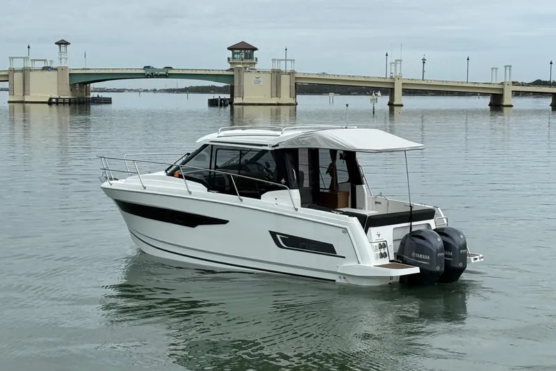 Slide: The Image of 2019 Jeanneau NC 895 boat on calm water near a bridge, featuring twin Yamaha engines. - 5