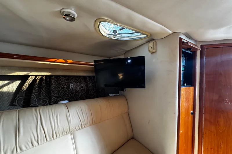 Slide: The Image of Interior of a 2005 Cobolt 36 boat with TV, beige seating, and wooden cabinetry. - 24