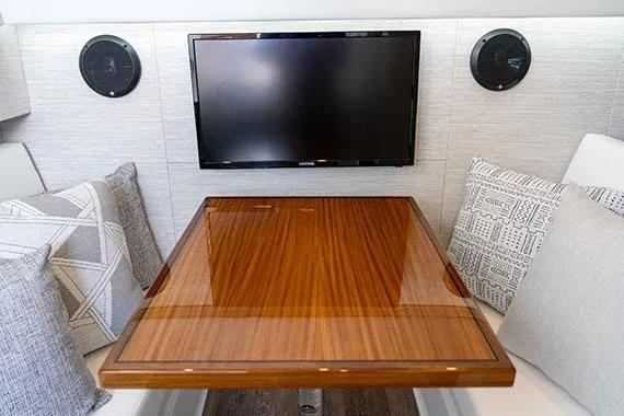 Slide: The Image of Manufacturer Provided Image: Interior of 2026 Cruisers Yachts 34 GLS I/O with TV, wooden table, and cushions. - 26