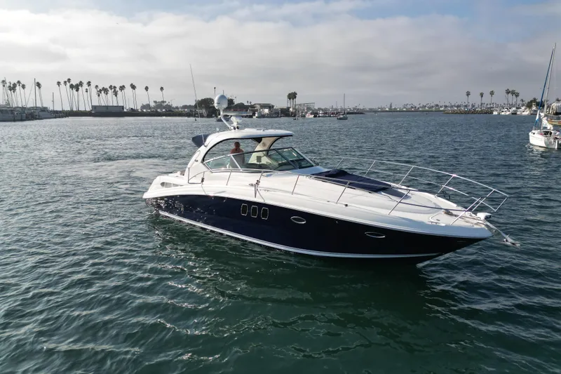 Slide: The Image of 2006 Sea Ray 38 Sundancer yacht cruising in a scenic harbor setting. - 2