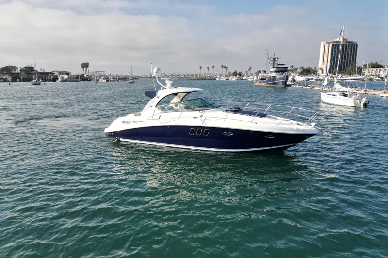Slide: The Image of 2006 Sea Ray 38 Sundancer yacht cruising in a marina with cityscape background. - 3