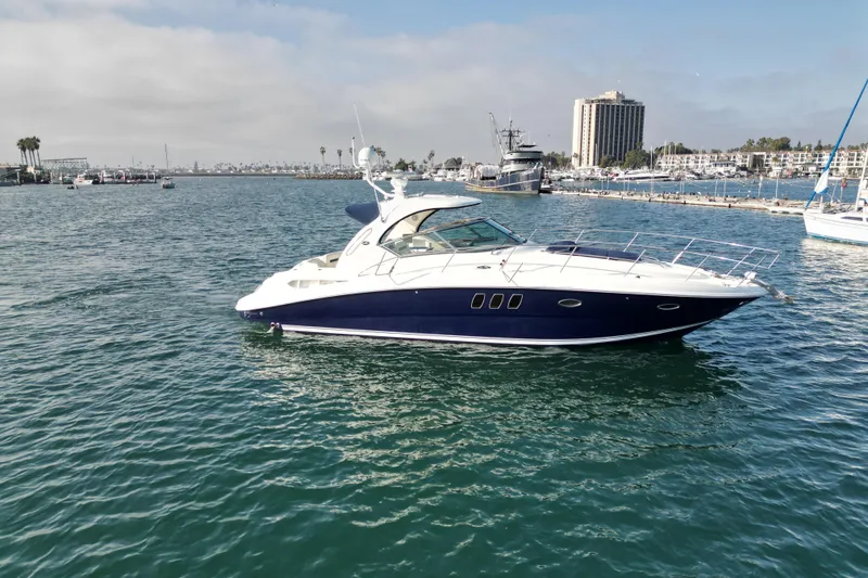 Slide: The Image of 2006 Sea Ray 38 Sundancer yacht cruising in a marina with cityscape background. - 4