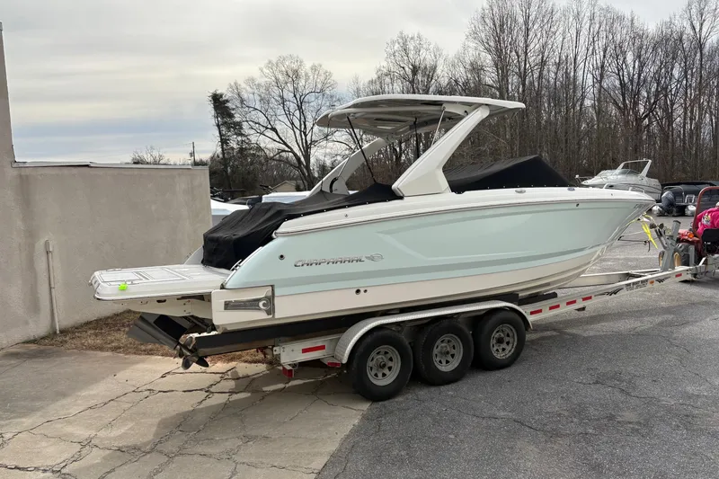 Slide: The Image of 2021 Chaparral 30 Surf boat on a trailer, parked outdoors near trees. - 6