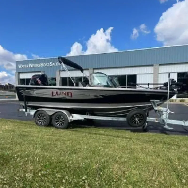 The Image of 2026 Lund 1975 Tyee boat in showroom, featuring sleek design and powerful outboard motor. - 1