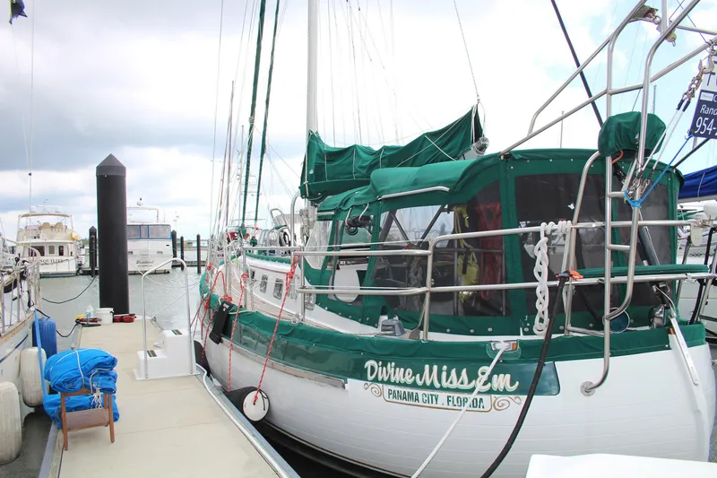 Slide: The Image of Sailboat docked at marina, Slocum 43 model, 1990, with green canopy and "Divine Miss Em" name. - 3