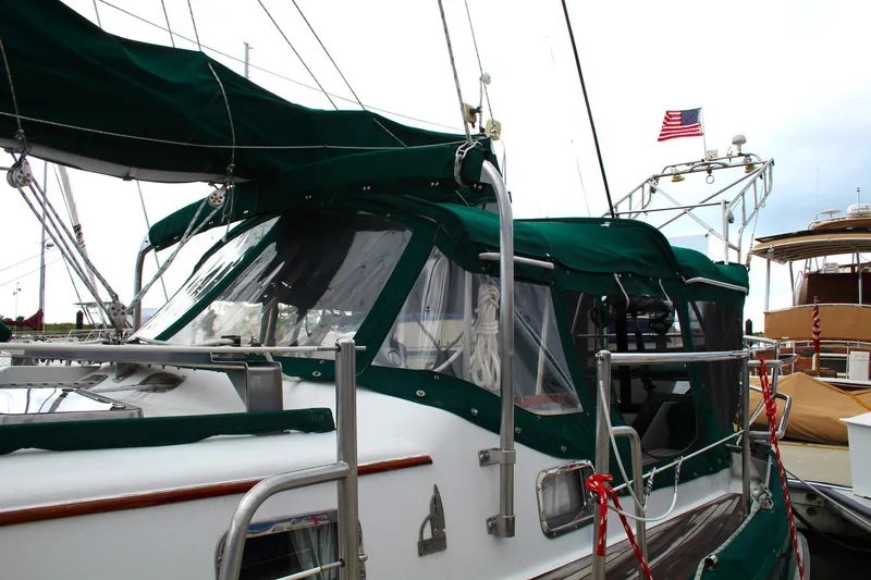 Slide: The Image of Sailboat with green canopy, Slocum 43, 1990 model, docked with American flag. - 7