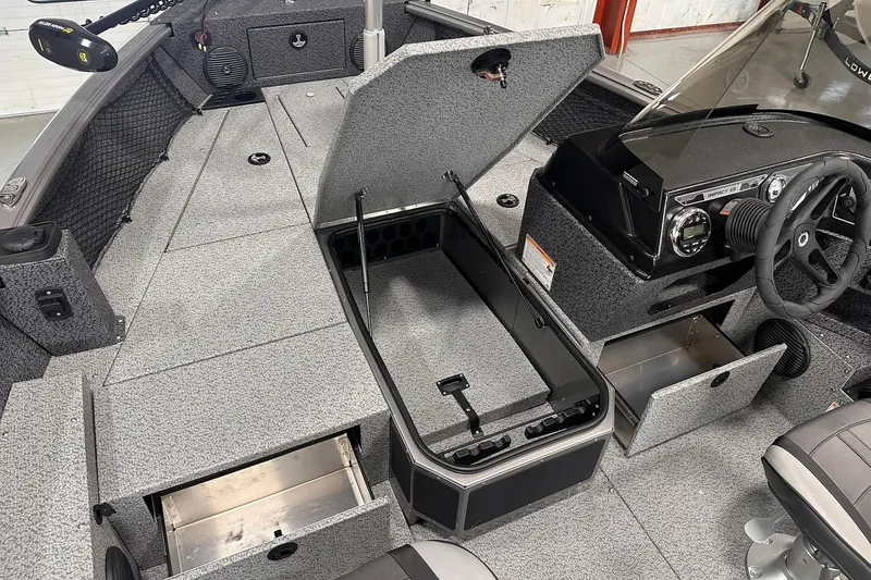 Slide: The Image of 2026 Lund 1775 Impact XS SS boat interior with open storage compartments and steering console. - 20