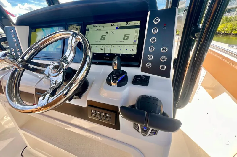 Slide: The Image of 2025 Robalo R302 Center Console boat interior with tan seating, dockside view. - 14