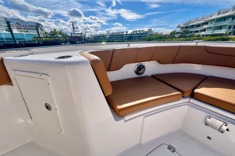 Slide: The Image of 2025 Robalo R302 Center Console boat with tan seating, docked near waterfront condos. - 16