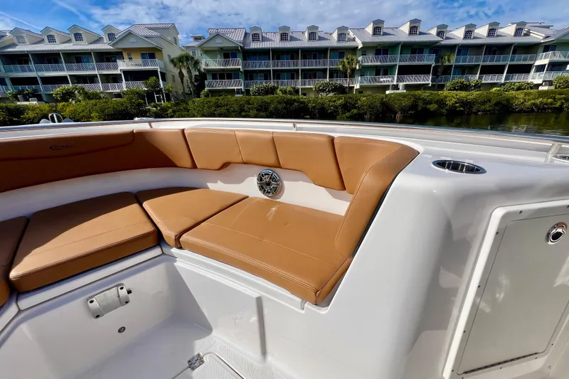 Slide: The Image of 2025 Robalo R302 Center Console boat with tan seating, docked near waterfront homes. - 18