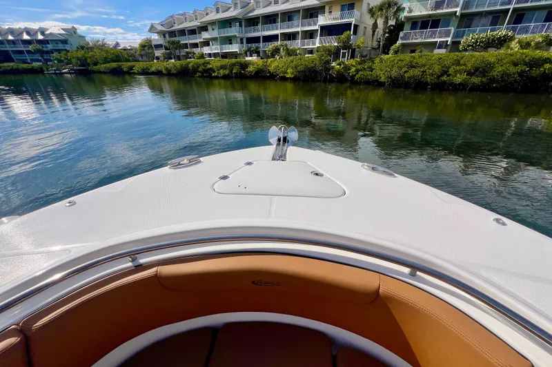 Slide: The Image of 2025 Robalo R302 Center Console boat with tan seating, docked near waterfront homes. - 19