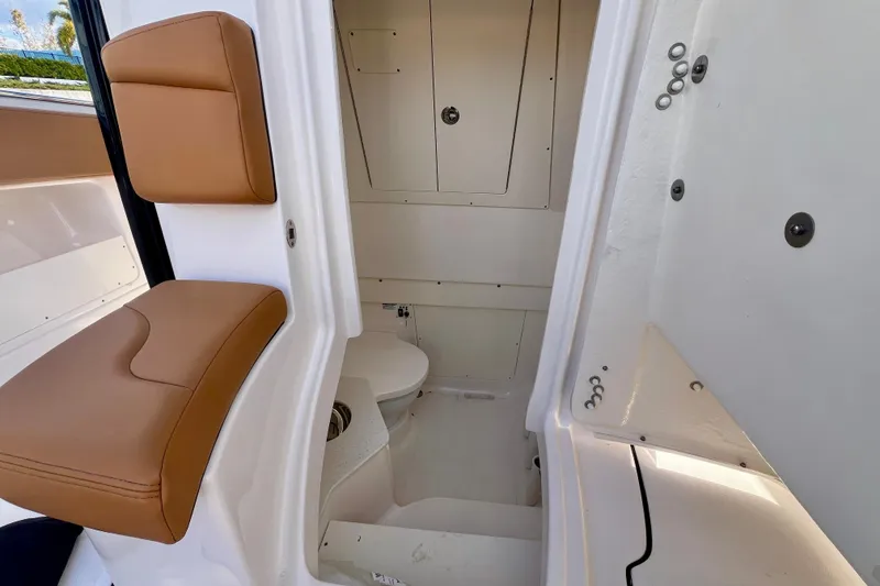 Slide: The Image of 2025 Robalo R302 Center Console boat interior with tan seating, docked by waterfront homes. - 22