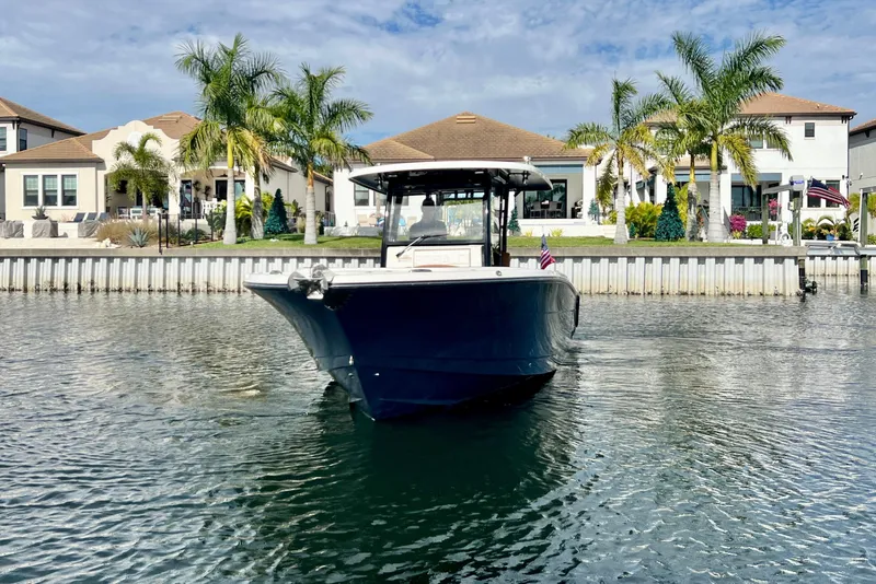 Slide: The Image of 2025 Robalo R302 Center Console boat on water, with waterfront homes and palm trees in background. - 3