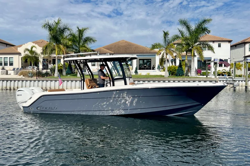 Slide: The Image of 2025 Robalo R302 Center Console boat on water, with palm trees and houses in background. - 5